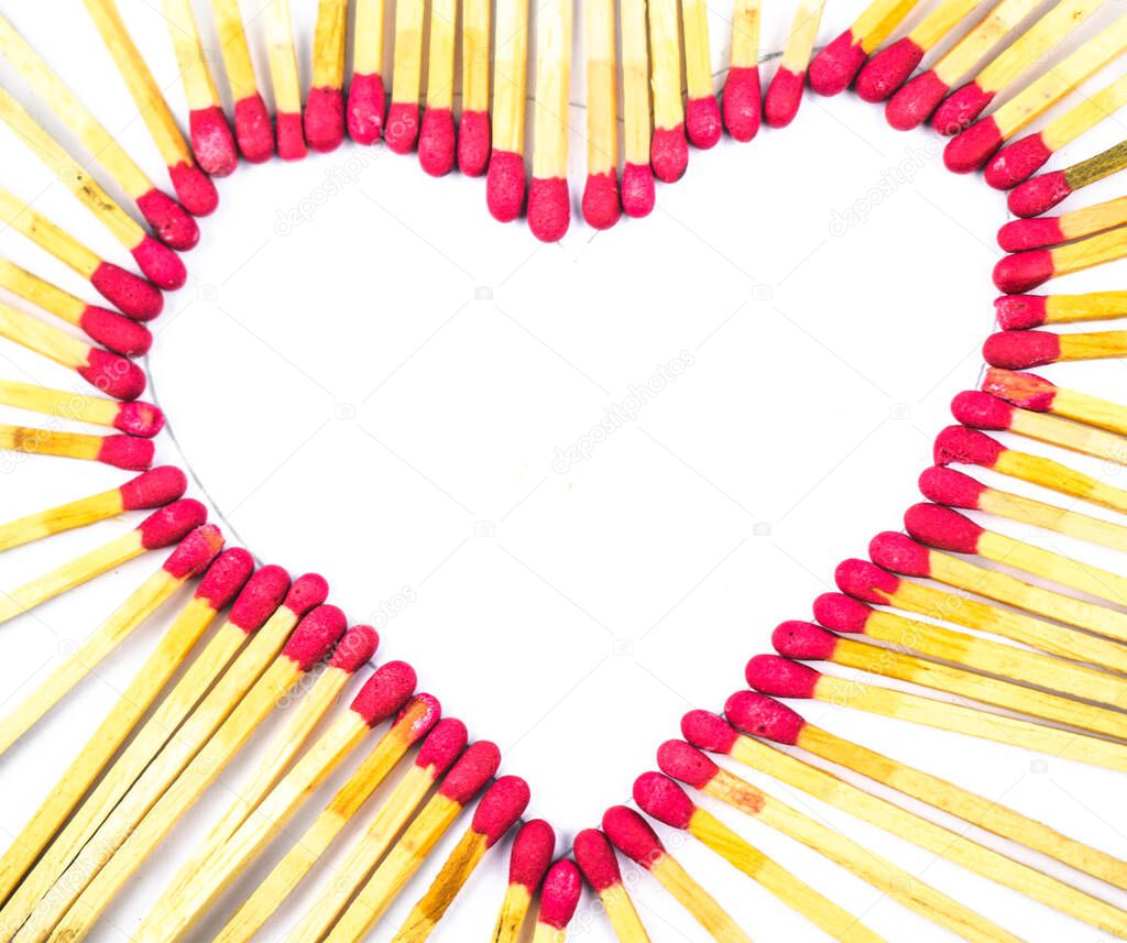 Heart made with red colored match sticks in front of a white isolated background