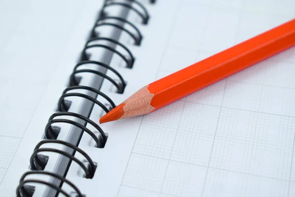 白い螺旋紙のノートブックの上に置かれたオレンジ色の木製の鉛筆クレヨン — ストック写真