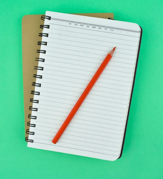 薄い青の紙の背景の上に2つのノートの紙の日記の上に置かれた赤い鉛筆 — ストック写真