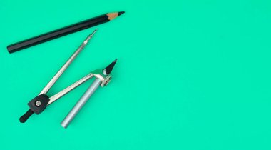 Pusula ve açık mavi kağıt arkaplana yerleştirilmiş bir siyah renkli tahta kalem.