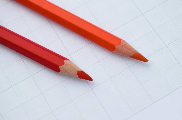 赤とオレンジの木の鉛筆クレヨンが白い紙の背景の上に置かれています — ストック写真