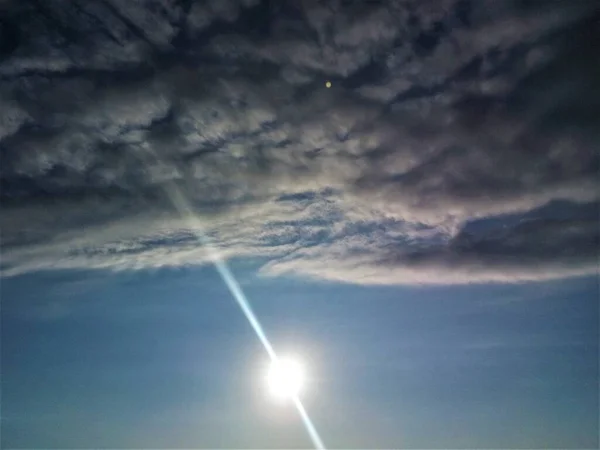 明るい太陽の円盤とその光線は羊の毛のような巨大な雲の下にあります — ストック写真