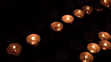 Birçok küçük mum karanlık bir odada yanar.