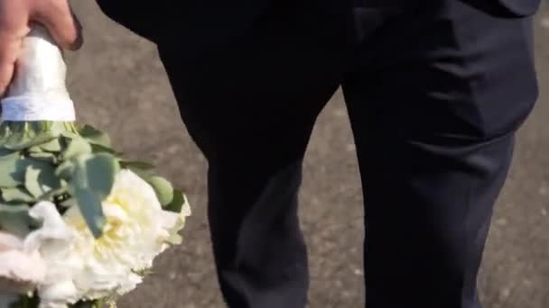 男は最愛のガールフレンドへのアスファルトのパスに沿って彼の手に花束で歩く — ストック動画