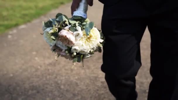 一个男人手握一束鲜花 沿着柏油路走向他心爱的女朋友 — 图库视频影像