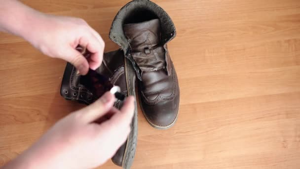 一个男人在一张木制桌子上的旧的 磨损的 棕色的鞋子的背景上旋转着一管胶水 这是特写 — 图库视频影像