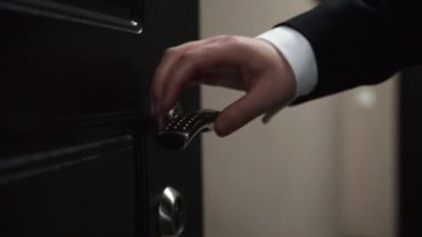 Smokinli bir adam otel odasının kapısını açar, yakın plan.