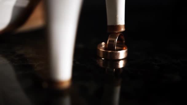 黄金の結婚指輪はベージュの靴の女性のかかとの下に立つ — ストック動画