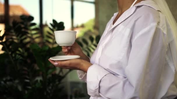 Meisje Een Wit Shirt Drinkt Koffie Terwijl Een Kruis Zit — Stockvideo