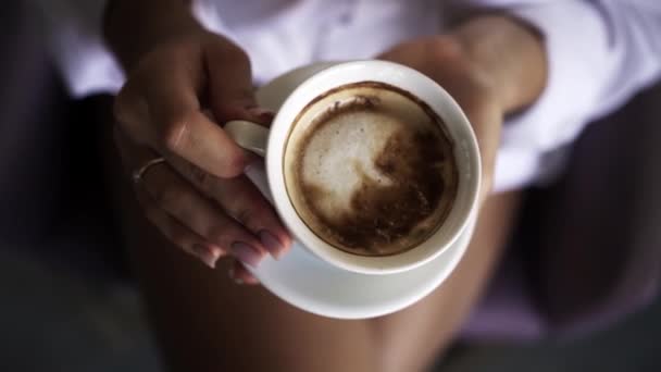 Menina Uma Camisa Branca Bebe Café Enquanto Sentado Uma Cruz — Vídeo de Stock