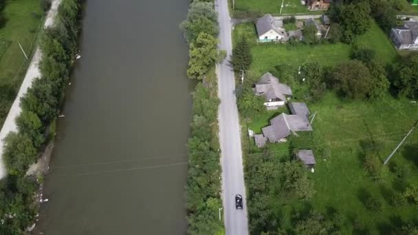 Voiture noire roule sur une route près de la rivière, cadre d'en haut, avec une vue d'oiseau 