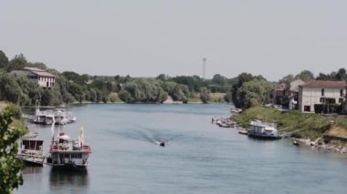 Bir kayığın yüzdüğü iki kıyı arasında bir nehir, içinde bir adam ve bir kadın oturuyor, üst manzara.