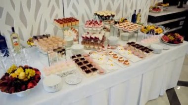 Büyük, güzel, açık büfe, alkollü içecekler, tatlı atıştırmalıklar beyaz bir masada ve tatilde misafirleri bekliyor..