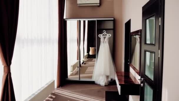 大きな鏡のようなクローゼットのドアの上にある美しい茶色のホテルの部屋では 長い白いドレスが窓にかかっています — ストック動画
