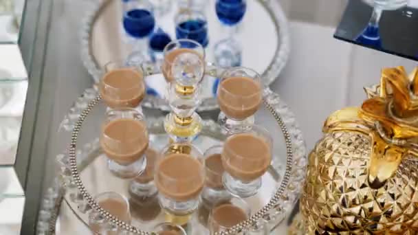 ビュッフェテーブルの美しいミラートレイには 小さなガラスで青い色のアルコール ミルク コーヒードリンクがあり その隣には黄金のパイナップルの形をした装飾的なガラスがあります — ストック動画