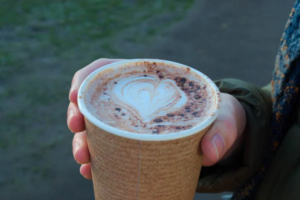 Cardboard coffee cup with a drawing of a heart in the foam