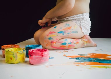 Küçük çocuğun ayakları boyayla lekelenmiş.