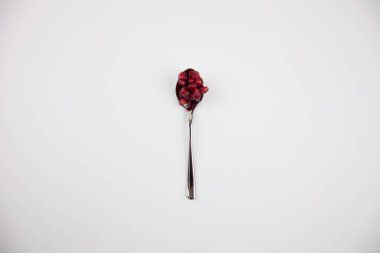 Beyaz arka planda demir kaşıkta nar.