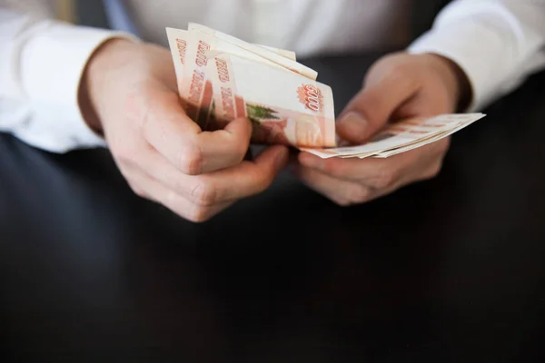 Beyaz gömlekli bir adam Rus kağıt parası sayıyor.