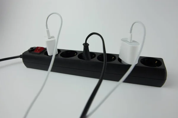 Beyaz arkaplandaki elektrik ağına bağlı bir telefonu şarj etmek için kablolar