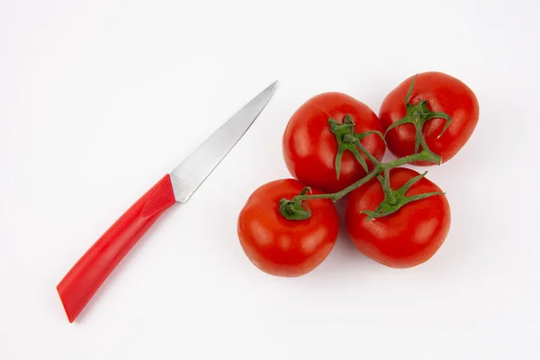 Kırmızı saplı bir bıçak ve beyaz arka planda taze domatesler. Salata için sebze..