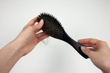 Beyaz arka planda saçı dökülmüş bir tarak tutan bir kız. Saç dökülmesi sorunu. Yaşam tarzını ve saç ve kafa derisi bakımını tanıtmak için..
