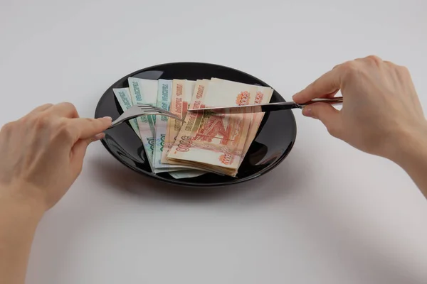 Rus parası tabakta, çatal ve bıçağın yanında. Tüketici kültürü. Yemek yerine para..
