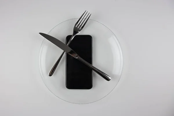 一把铁叉和一把带电话的刀放在透明的盘子里 电话信息消费文化 图库图片