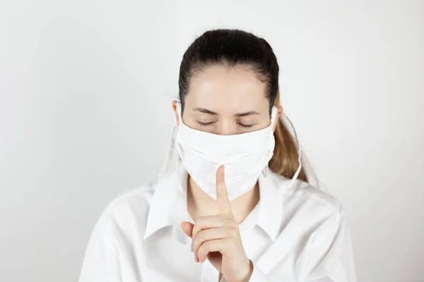 Hapşırmadan bir saniye önce maskeli genç bir kız. Dikkat çekmek için parmağıyla işaret ediyor. Salgın sırasında yaşam.