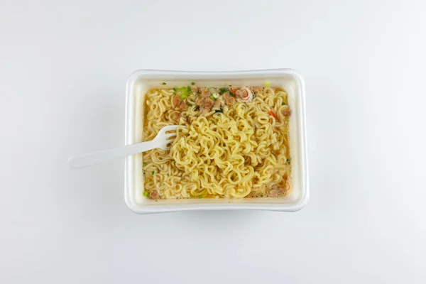 白色背景上的塑料叉子和方便面 为了快速的食物演示 垃圾食品 不健康的生活方式 图库图片