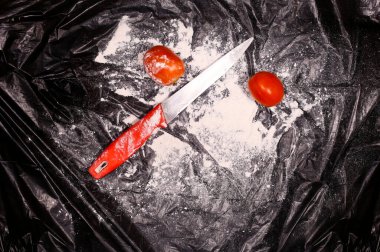 Tozlu, yaratıcı, koyu renk arka planda domatesli kırmızı renk bıçak.