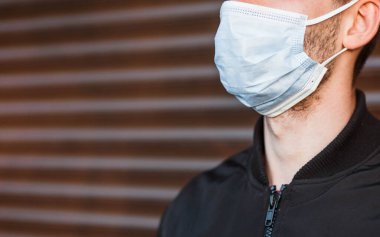 Koronavirüs salgınına karşı koruyucu maske takan genç bir adamın pankart kaplama görüntüsünü kapatın. Kadın hasta, covid-19 pandemik yayılma, salgın hastalık ve korona konseptinden korunuyor..
