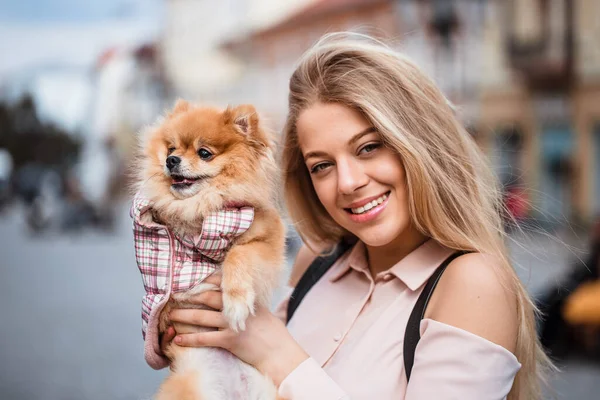 The dog kisses and sniffs the girl. Portrait of girl and dog on city background. The dog is man\'s best friend.