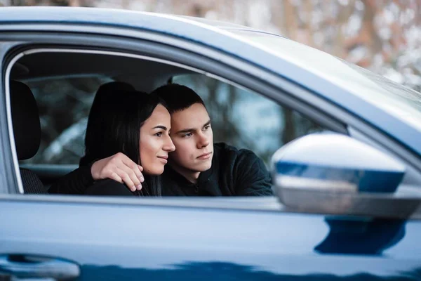 Beautiful couple talking and smiling while sitting in their car. A happy young couple is sitting. Travel and adventure concept. Traveling in comfort. Love in the car.