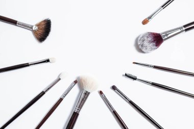 Düz görünüm, arka planda profesyonel makyaj fırçaları. Metnin için alanı kopyala. Beyaz arka planda makyaj brushe. Çeşitli fırçaların havadan görünüşü. Çeşitli makyaj fırçası boyutları.
