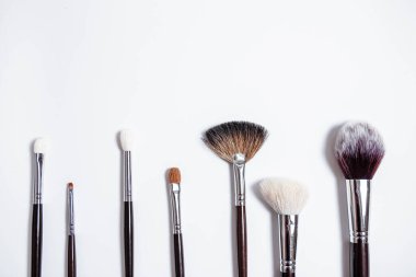 Düz görünüm, arka planda profesyonel makyaj fırçaları. Metnin için alanı kopyala. Beyaz arka planda makyaj brushe. Çeşitli fırçaların havadan görünüşü. Çeşitli makyaj fırçası boyutları.