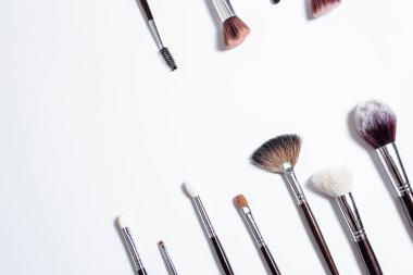 Düz görünüm, arka planda profesyonel makyaj fırçaları. Metnin için alanı kopyala. Beyaz arka planda makyaj brushe. Çeşitli fırçaların havadan görünüşü. Çeşitli makyaj fırçası boyutları.