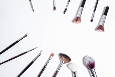 Düz görünüm, arka planda profesyonel makyaj fırçaları. Metnin için alanı kopyala. Beyaz arka planda makyaj brushe. Çeşitli fırçaların havadan görünüşü. Çeşitli makyaj fırçası boyutları.