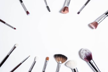 Düz görünüm, arka planda profesyonel makyaj fırçaları. Metnin için alanı kopyala. Beyaz arka planda makyaj brushe. Çeşitli fırçaların havadan görünüşü. Çeşitli makyaj fırçası boyutları.
