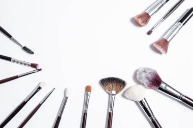 Düz görünüm, arka planda profesyonel makyaj fırçaları. Metnin için alanı kopyala. Beyaz arka planda makyaj brushe. Çeşitli fırçaların havadan görünüşü. Çeşitli makyaj fırçası boyutları.