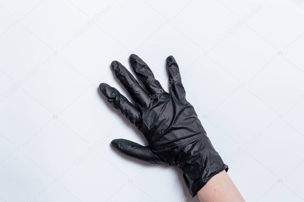 Hand in black gloves of a doctor or hairdresser on a white background. Gloves are worn on the hand. The girl puts a black glove on her hand. Black mitten on his hand.