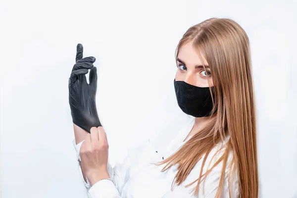 Viral koruyucu giysi ve tıbbi maske takan bir virüs uzmanı siyah eldivenlerle el ele tutuşup koronavirüs salgınının sonuçlarını düşünüyor. Doktor siyah tıbbi eldiven giyiyor..