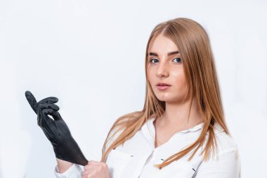 Makyaj yapan güzel bir genç kadın. Yüzüne pudra sürmek için elinde fırça olan bir kız. Siyah eldivenli kadın makyaj yapar. Kadın beyaz arka planda makyaj yapıyor..