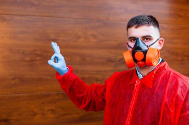 Hastalığa karşı koruyucu maske takan kırmızı elbiseli bir doktorun portresi. Doktor her şeyin yoluna gireceğini gösteriyor. Ahşap arka planda bir doktor. Metin için boş alan.