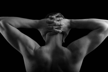 Kaslı, seksi vücutlu ve sırtı çıplak bir erkek sporcu. Adam geri döndü ve elleri siyah bir arkaplanda. Sırtı ve kolları şişmiş..