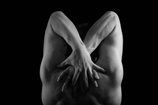 Kaslı, seksi vücutlu ve sırtı çıplak bir erkek sporcu. Adam geri döndü ve elleri siyah bir arkaplanda. Sırtı ve kolları şişmiş..