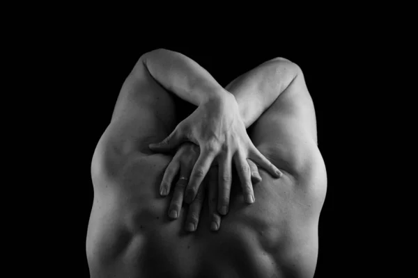 Kaslı, seksi vücutlu ve sırtı çıplak bir erkek sporcu. Adam geri döndü ve elleri siyah bir arkaplanda. Sırtı ve kolları şişmiş..