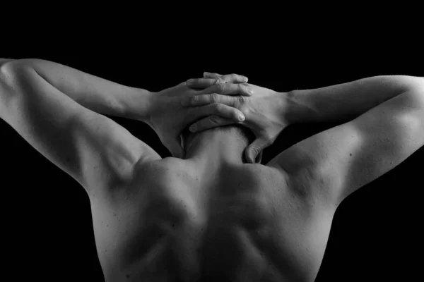 Male model athlete with muscular sexy body and bare back. Man\'s back and hands on a black background. Pumped back and arms.