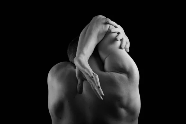 Kaslı, seksi vücutlu ve sırtı çıplak bir erkek sporcu. Adam geri döndü ve elleri siyah bir arkaplanda. Sırtı ve kolları şişmiş..