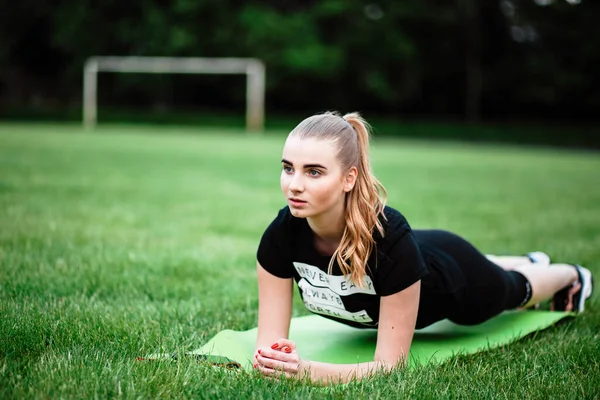 Healthy sports lifestyle. Athletic young woman in a sports dress doing fitness exercises.Fitness woman at the stadium.A young girl shakes a press on the carpet.The girl on the lawn goes in for sports.